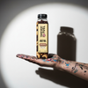 Transparent Fuel Bottled Trail Mix in Coffee Bean + Chocolate Chip Flavor on an artist's hand covered in paint