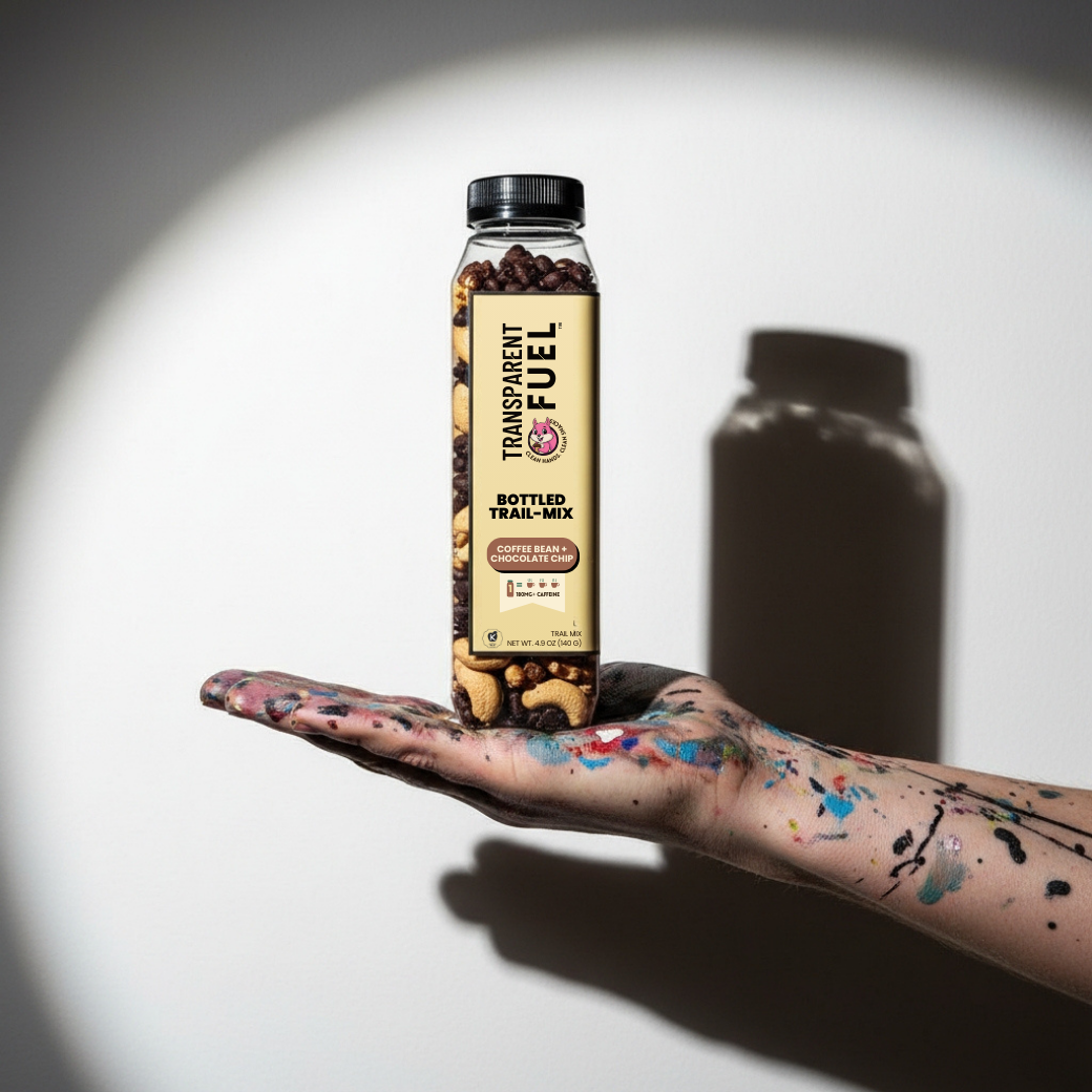 Transparent Fuel Bottled Trail Mix in Coffee Bean + Chocolate Chip Flavor on an artist's hand covered in paint